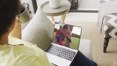 Video-Einer-Person,-Die-Auf-Der-Couch-Sitzt-Und-Sich-Ein-Fußballspiel-Auf-Dem-Laptop-Ansieht