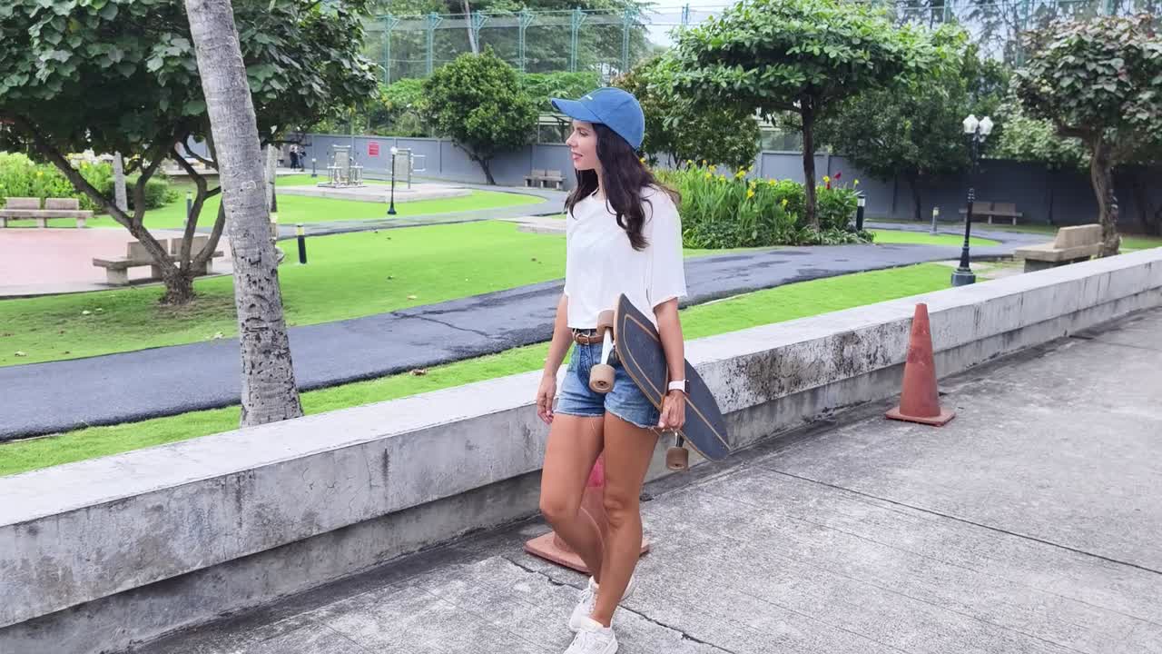 Wanita berjalan dengan longboard di taman