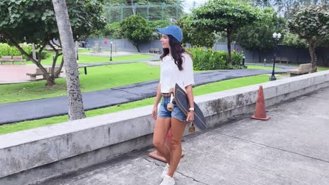 woman walking with a longboard in a park