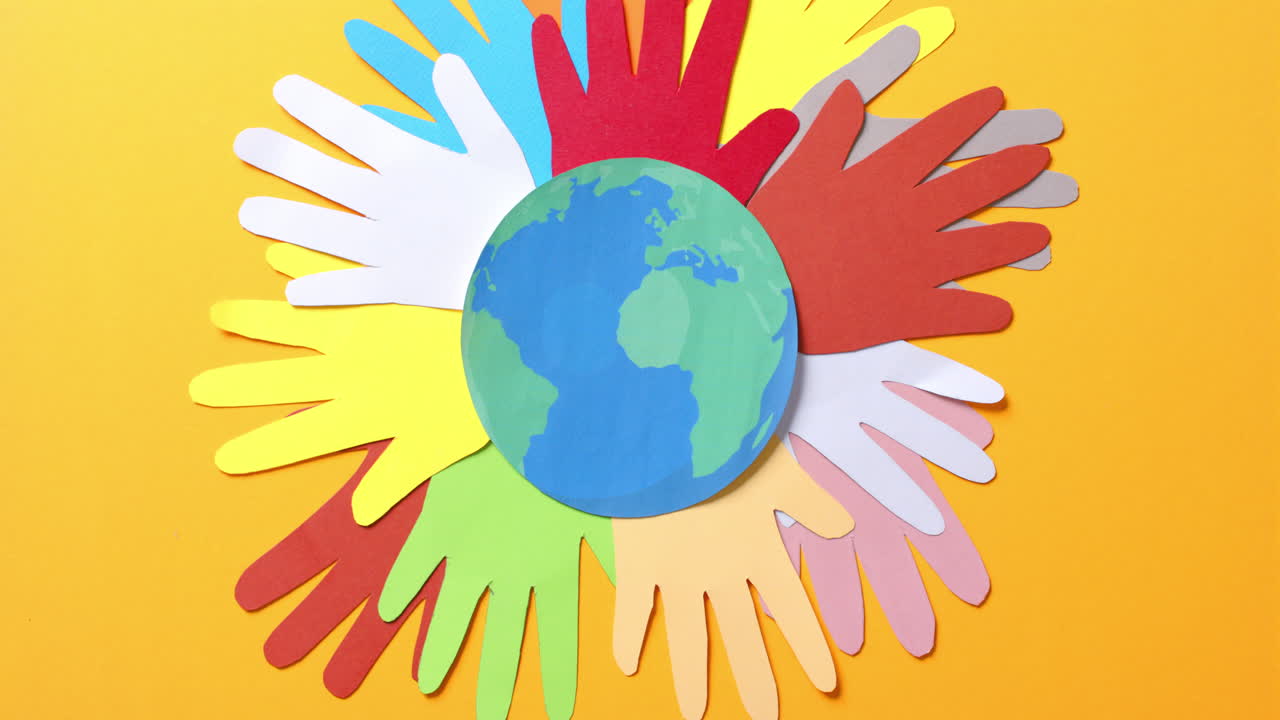 복사 공간이 있는 노란색 배경에 있는 다채로운 종이로 만든 지구와 함께 손을  ⁇ 습니다.