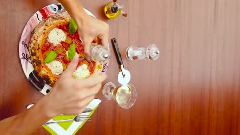 Vertical-video-of-a-man-peppering-his-beautiful-looking-fresh-Italian-pizza