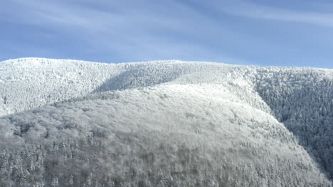 Steiler-Bergkamm-Mit-Wäldern-Im-Winterschnee,-Sonniger-Himmel,-Tschechien