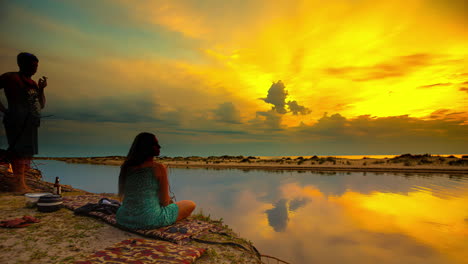 Pareja-Disfrutando-Del-Atardecer-Junto-Al-Agua-En-Timelapse-Con-Nubes-De-Tormenta-En-Movimiento