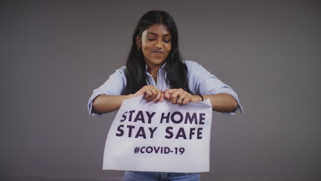 Young-Woman-Rips-Stay-Home-Stay-Safe-Sign