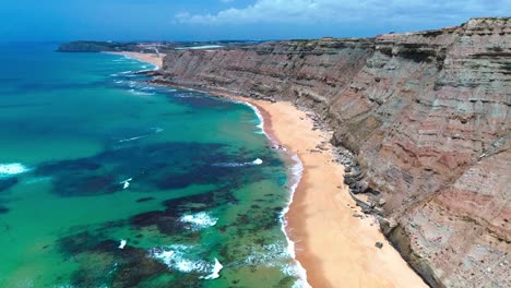 aerial-view-of-rugged-coast-line-with-blue-ocean-and-waves-crashing,-portugal,-4k