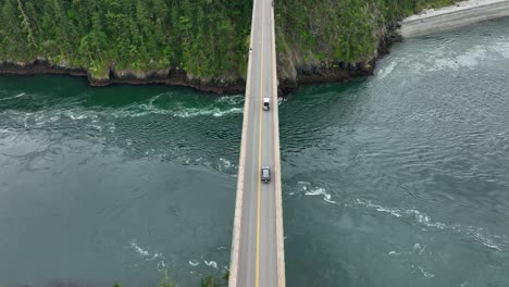 overhead aerial view of cars driving along the deception pass bridge over the pacific ocean