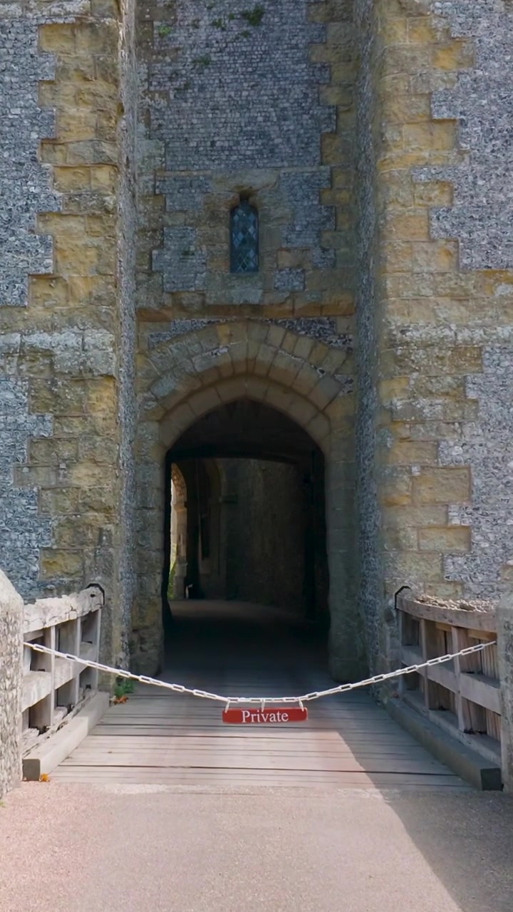 Un cartello privato blocca l'ingresso al Castello di Arundel mentre la telecamera si avvicina a una barriera a catena su un ponte, negando ai visitatori l'accesso al passaggio ristretto della portineria e all'area proibita. Formato verticale per i social