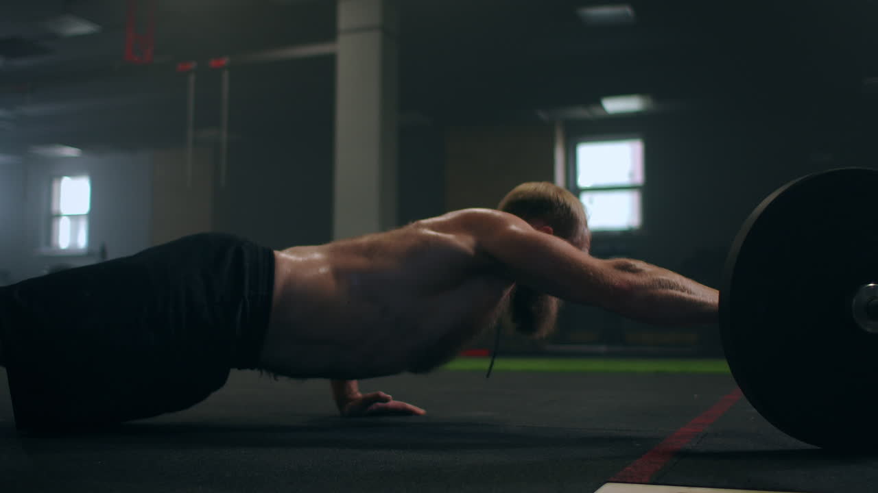 un hombre fuerte es presionado con una mano en el gimnasio con un vapor en su cuerpo.