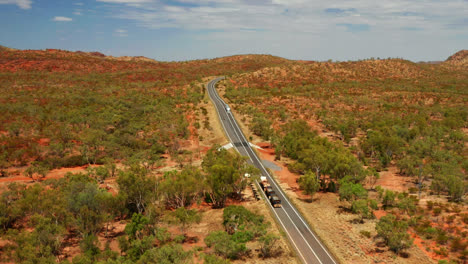 vehicles driving on country road among vegetation in queensland, australia - aerial drone shot