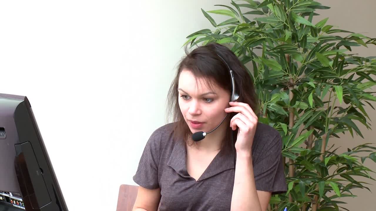 Smiling woman with headset on working at a computer