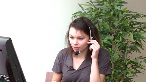 smiling woman with headset on working at a computer