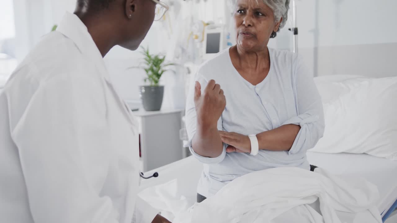 Diverse female doctor inspecting arm of concerned senior female patient, slow motion