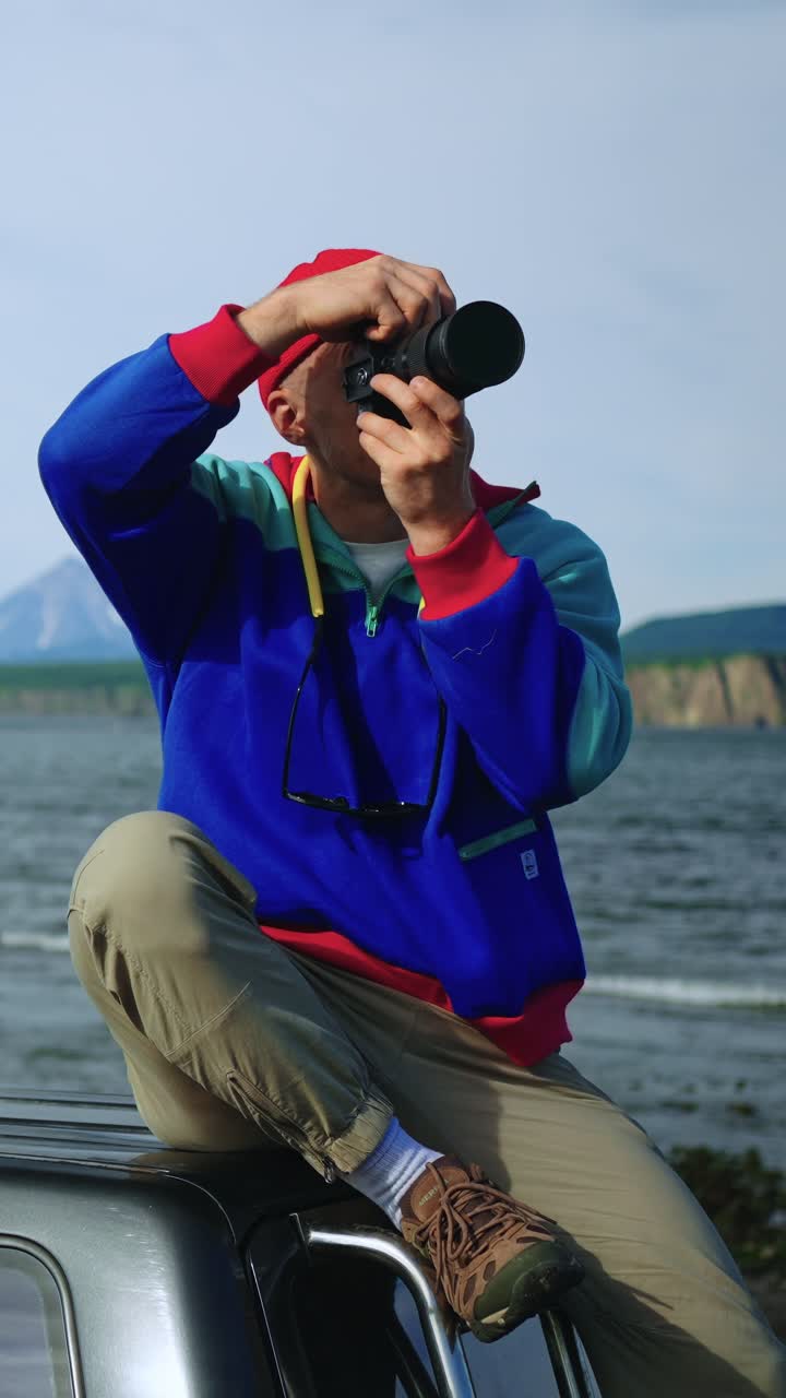 Adventurous Man Taking Photos from Car Roof by the Ocean