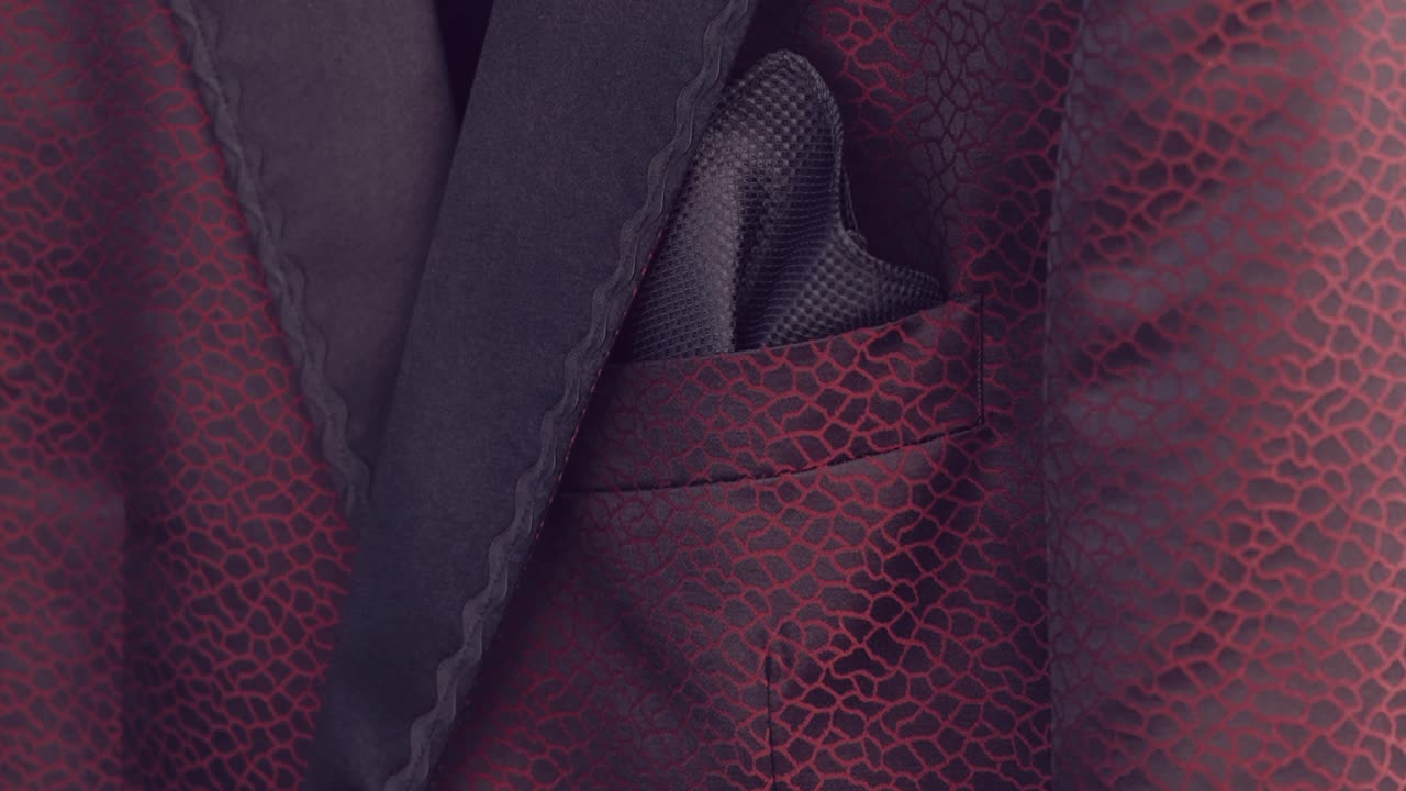 Close up of a red textured suit with a black pocket square