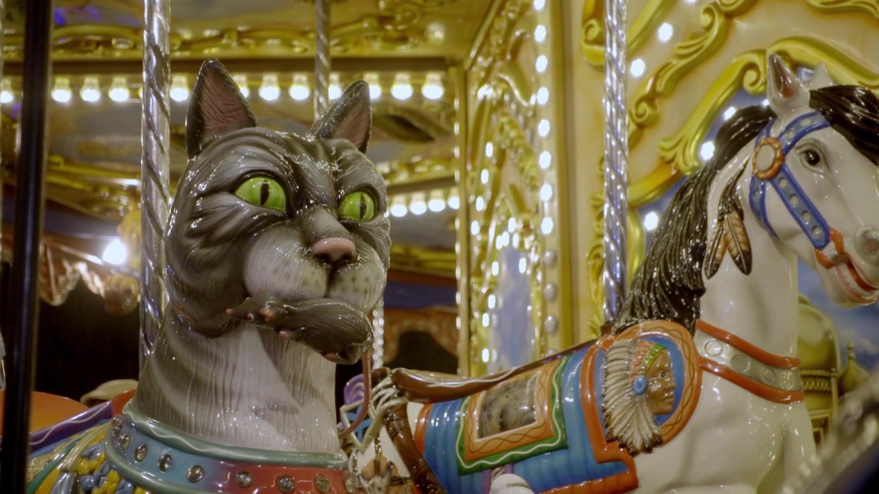 Close up of decorative carousel cat and horse figures illuminated with bright lights during amusement ride at festival in Cholula, Puebla, Mexico.
