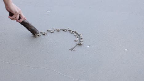 sequential drawing of a heart shape in sand