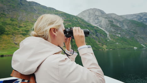 A-Woman-Is-Standing-On-The-Bow-Of-The-Ship-Looking-Through-Binoculars-Cruise-On-The-Fjords-Of-Norway