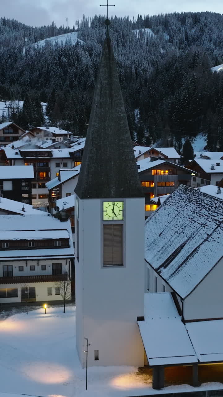 Aerial drone view of the Corvara village covered in snow at blue hour, in South Tyrol, Dolomites, in northern Italy. Vertical