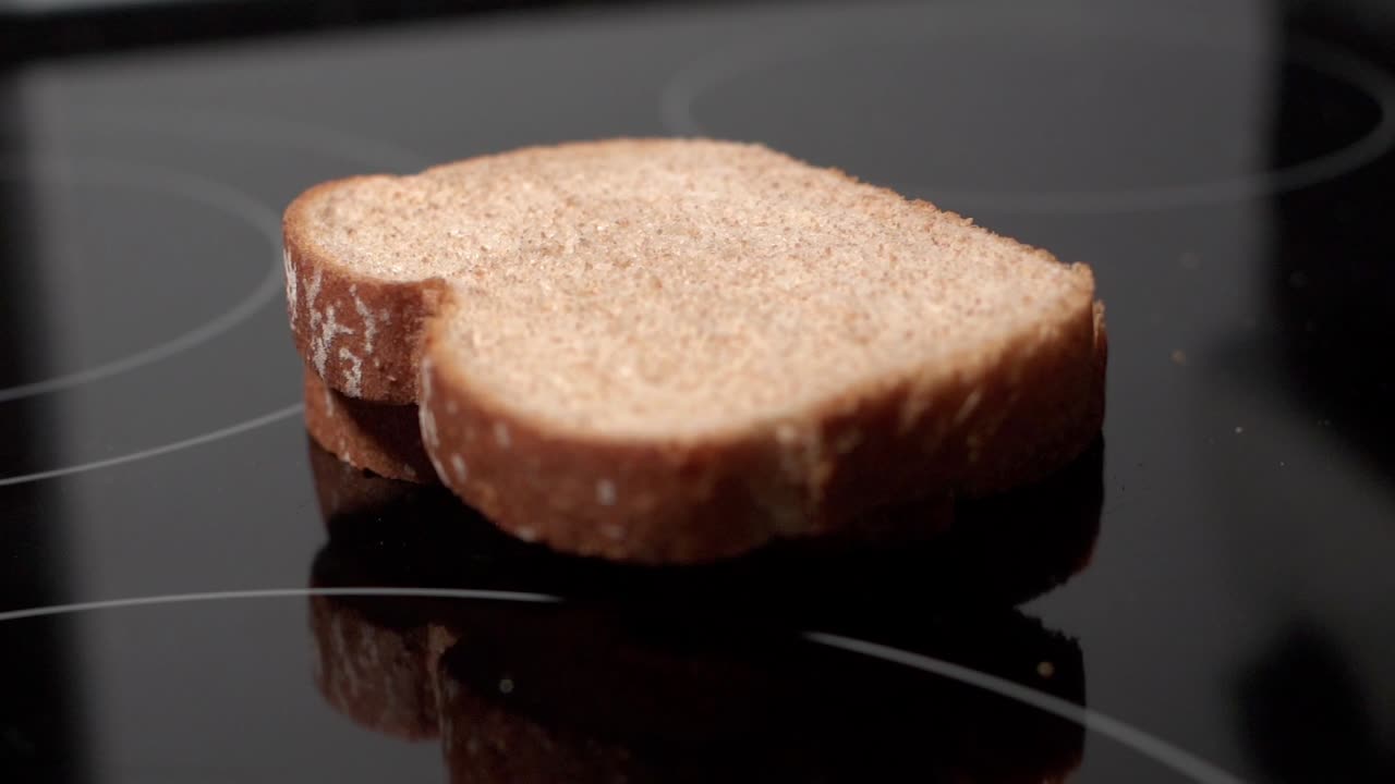 Fette di pane impilate che cadono e rimbalzano su una superficie da cucina nera riflettente