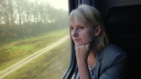 young woman travels by train looks out the window at beautiful scenery dreams slow motoin video