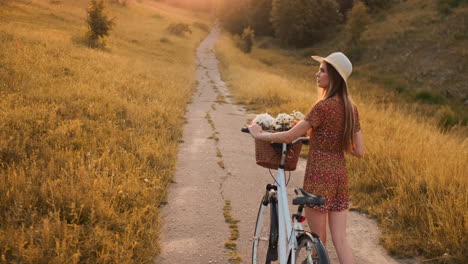 Lens-flare:-smiling-happy-woman-in-short-dress-is-riding-a-bicycle-with-a-basket-and-flowers-in-the-park-with-green-trees-around-during-the-dawn.-Slowmotion-shot