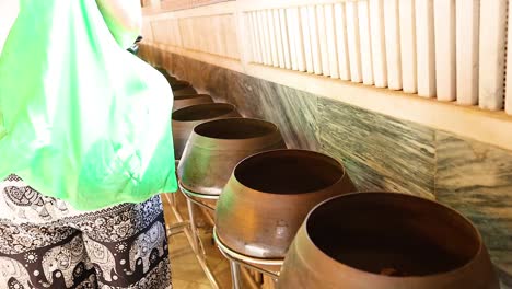 person donating coins into temple bowls