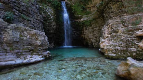 hermosa cascada con agua esmeralda rodeada de rocas altas en albania