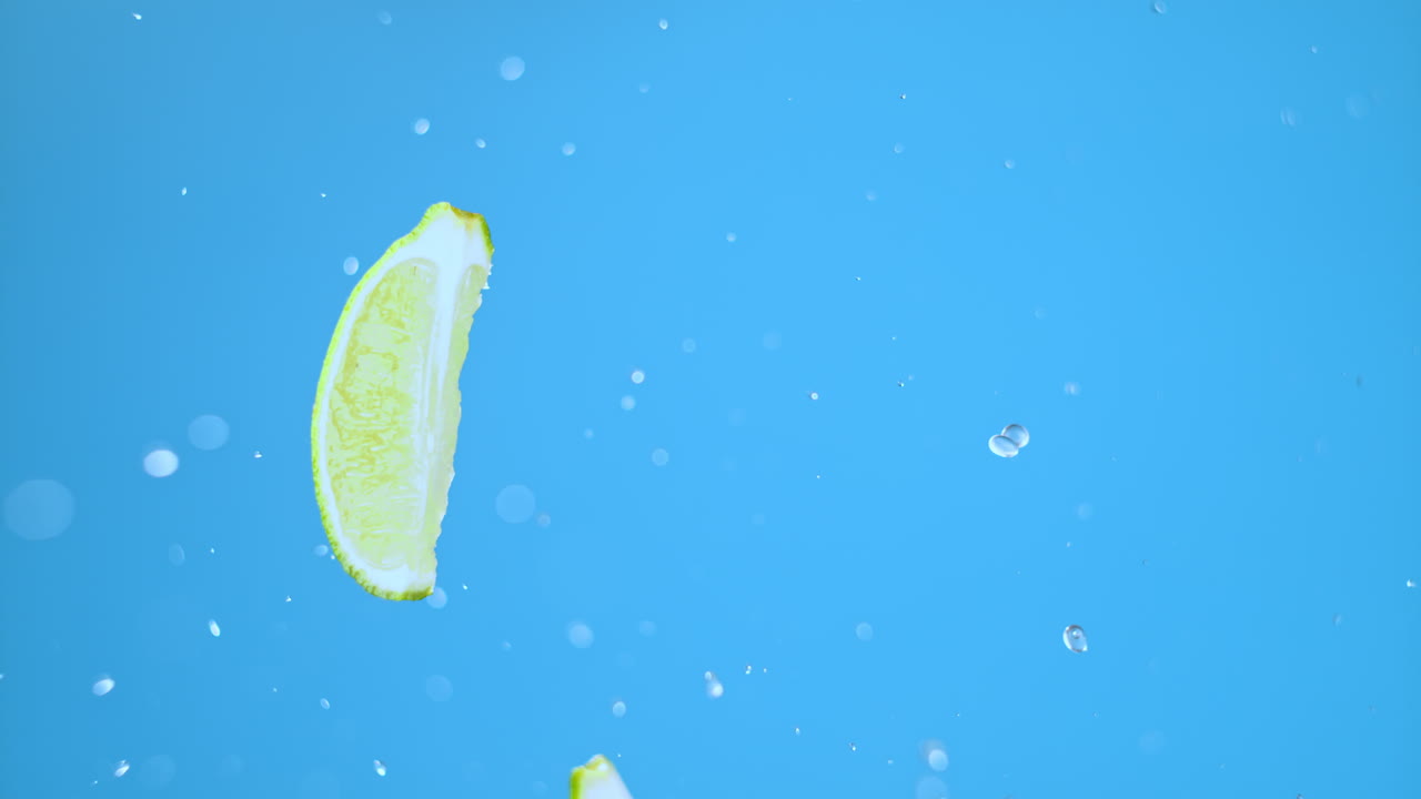 라임 조각은 물방울과 함께 공중에 뛰어다닙니다.