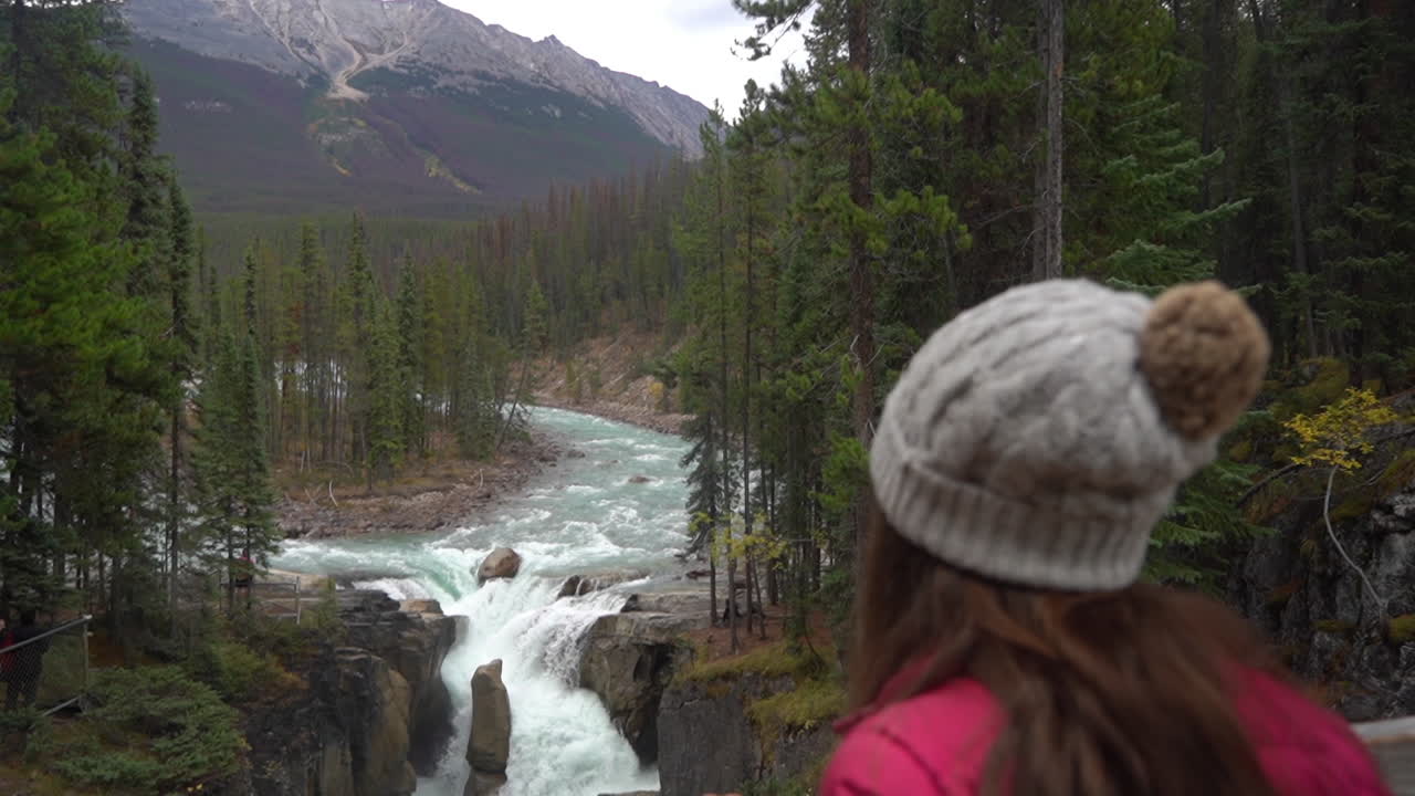 mujer en la pasarela mirando la pintoresca cascada, el cañón del río y el paisaje montañoso