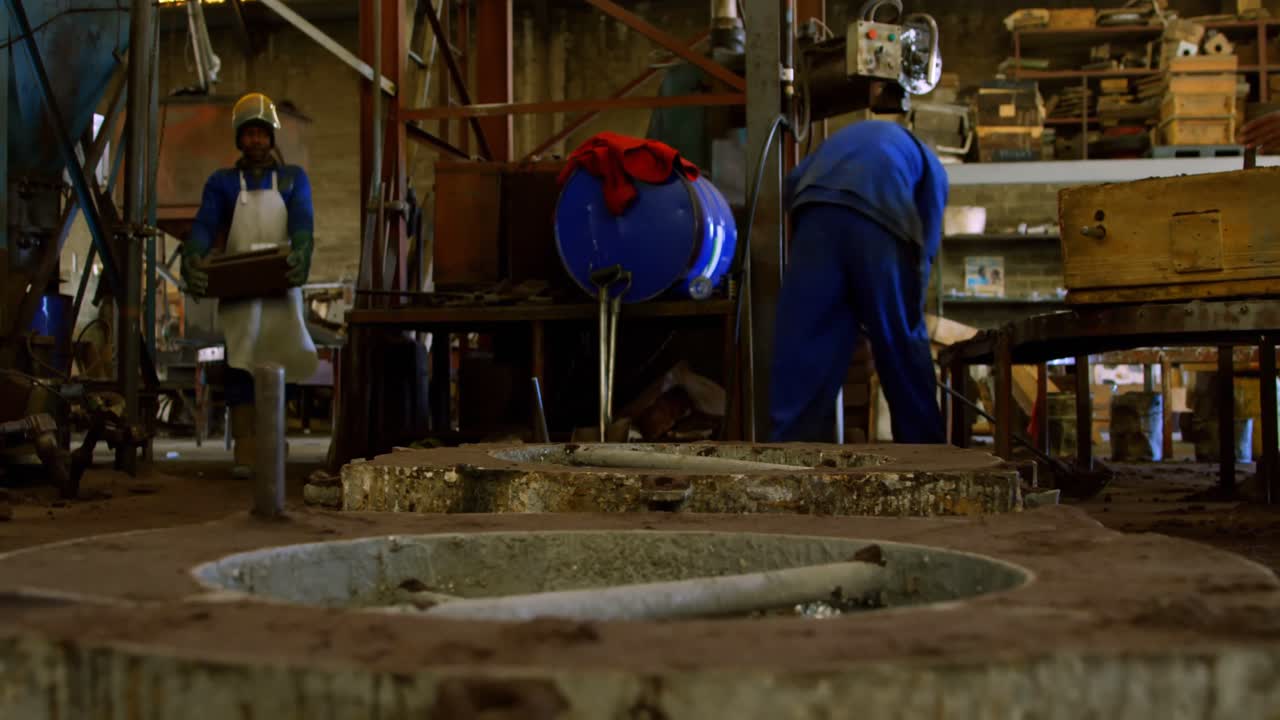 Worker cleaning with broom in foundry workshop 4k