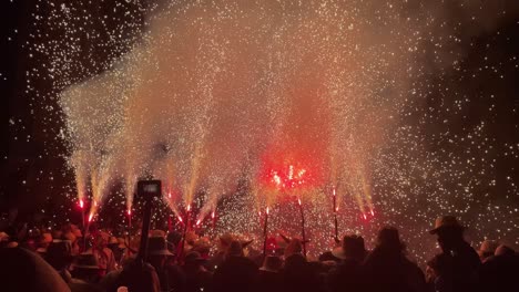 crowd gathers under fireworks during the traditional ball de diables in tarragona, spain