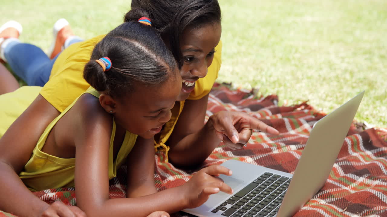 retrato de madre e hija están usando una computadora portátil en el jardín