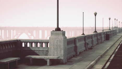 city walkway with benches and streetlights alongside a foggy river
