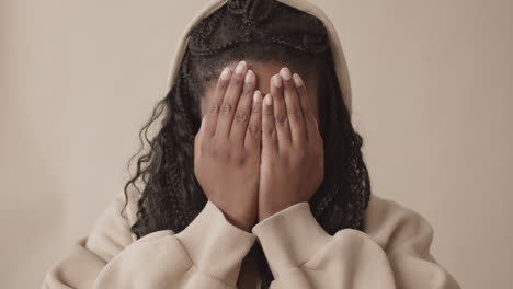 young african-american woman covering face with palms