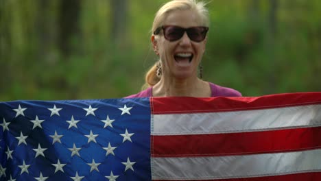 closeup of pretty, blonde woman holding up an american flag and motioning “yes” with her head