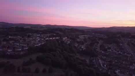 Toma-Aérea-De-Dolly-Lateral-Lateral,-Colorida-Puesta-De-Sol-Sobre-Los-Suburbios-De-Exeter,-Inglaterra