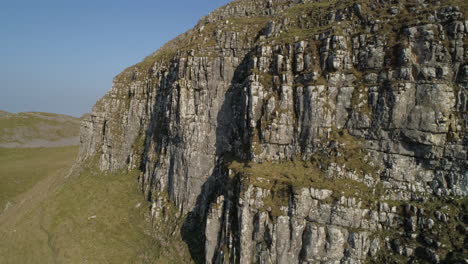 closeup aerial drone shot pulling away from warrendale knots yorkshire dales countryside grass and rocky hills on sunny summer day uk