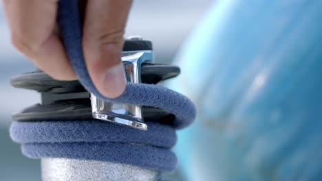 man's hand rolling rope on a boat winch while sailing in ocean
