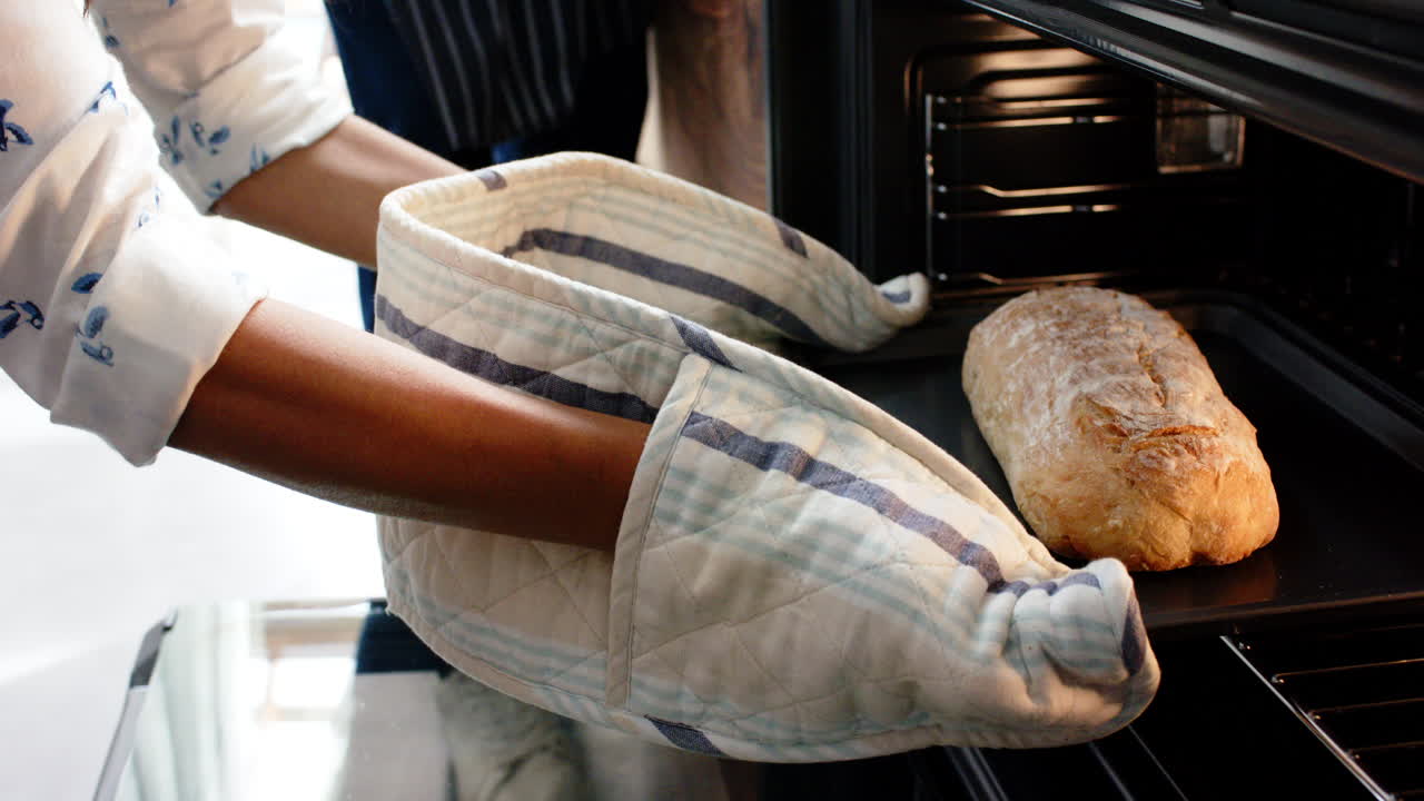 Biracial woman wearing apron and baking bread in kitchen, slow motion