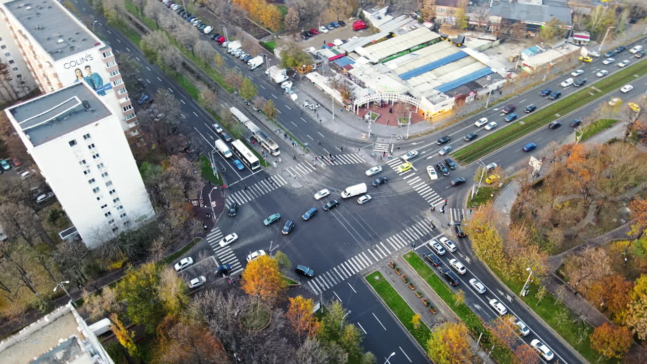 BUCHAREST, ROMANIA - DECEMBER 9, 2020: Crossroad with moving cars, people crossing the street, trams, bare trees and residential buildings, view from a drone, panorama