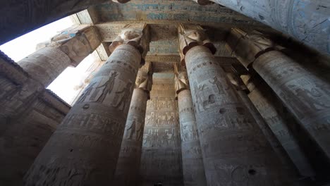 upward view of massive columns in dendera temple of hathor with hieroglyph carvings