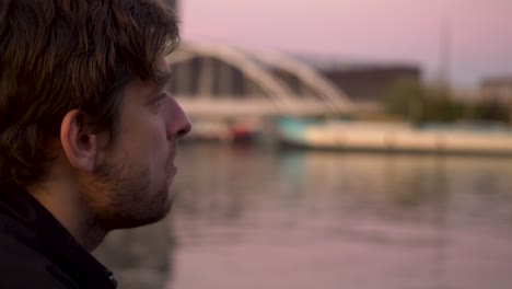 Close up profile shot of a handsome bearded man eating potato chips with a beautiful lake background