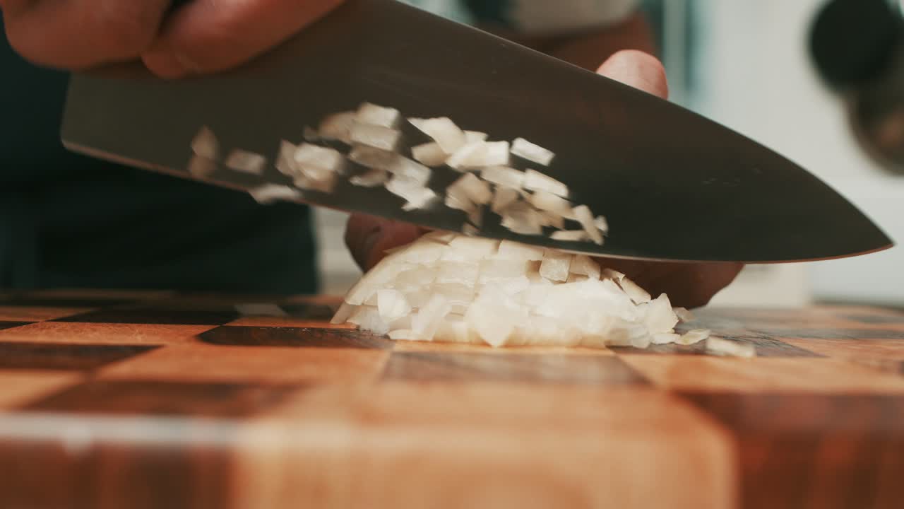 Slicing onion with big kitchen knife on wooden cut board