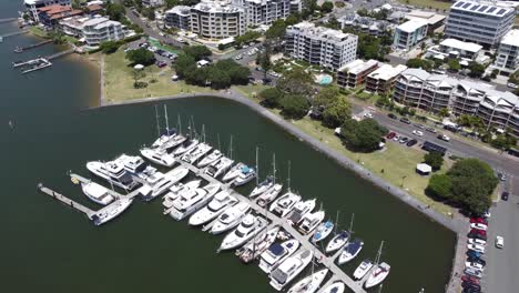 4k aerial view of a boat harbour flying towards high rise holiday apartments on australia's sunshine coast