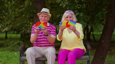 anciano elegante abuela abuelo mostrando apretando anti-estrés empujar pop es un juego de juguete popular