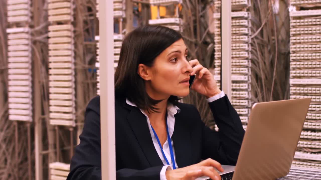 técnico hablando en teléfono móvil mientras usa una computadora portátil