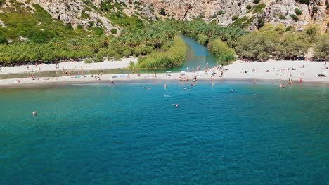 A-hidden-paradise-engulfed-in-the-rocky-arms-of-the-gorge-and-palm-forest-meeting-Preveli-beach,-Crete