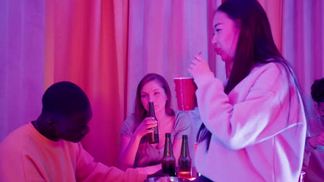 three multiethnic young friends spending time together, talking and drinking during a party at home