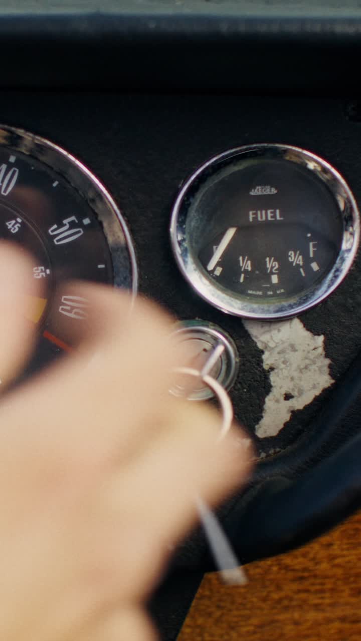 Person checking fuel gauge on a vintage car dashboard