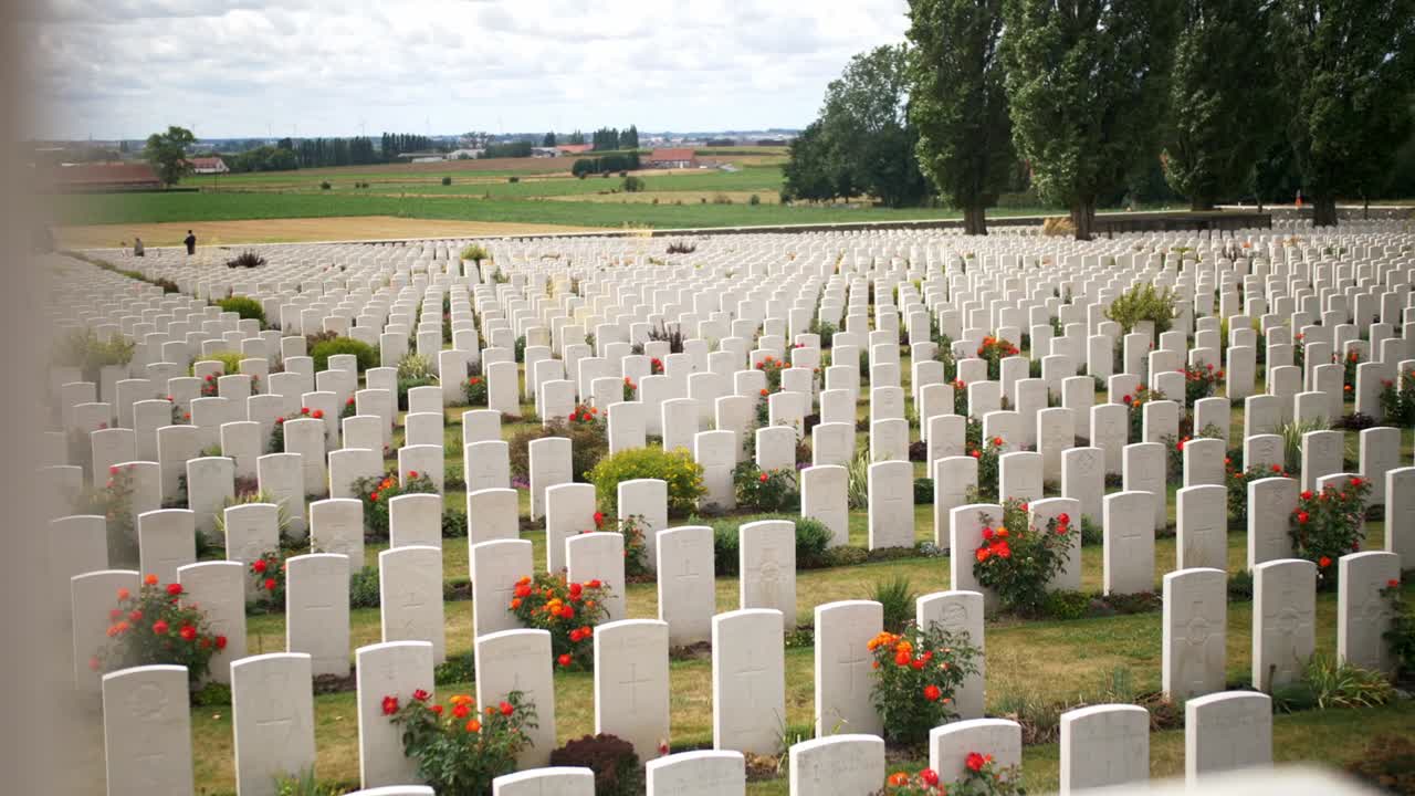 이프레 베글리움에 빨간 장미가 있는 아름다운 녹색 정원 사이에 있는 전쟁 기념 묘지의 비석, 슬라이딩 핸드헬드 샷